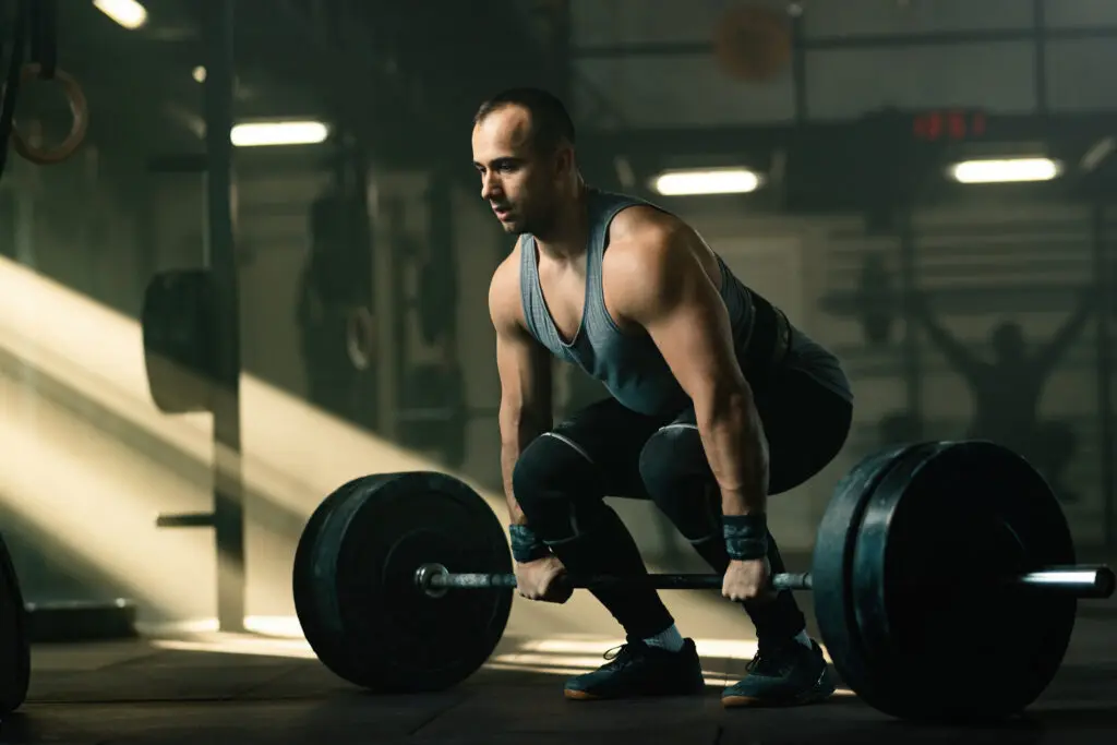 "Άτομο εκτελεί deadlift με μπάρα, αναδεικνύοντας τη σωστή και λανθασμένη στάση της πλάτης. Το κείμενο περιγράφει τα προβλήματα της κίνησης σε μόνο ένα επίπεδο (σάγγκαλ) και την ίση κατανομή βάρους, καθώς και τις εναλλακτικές ασκήσεις που προσφέρουν καλύτερη ενεργοποίηση της οπίσθιας αλυσίδας και μειώνουν τον κίνδυνο τραυματισμού."
